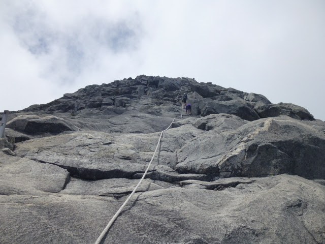 Climbers ascending the rope-assisted granite slabs near the summit of Mount Kinabalu.